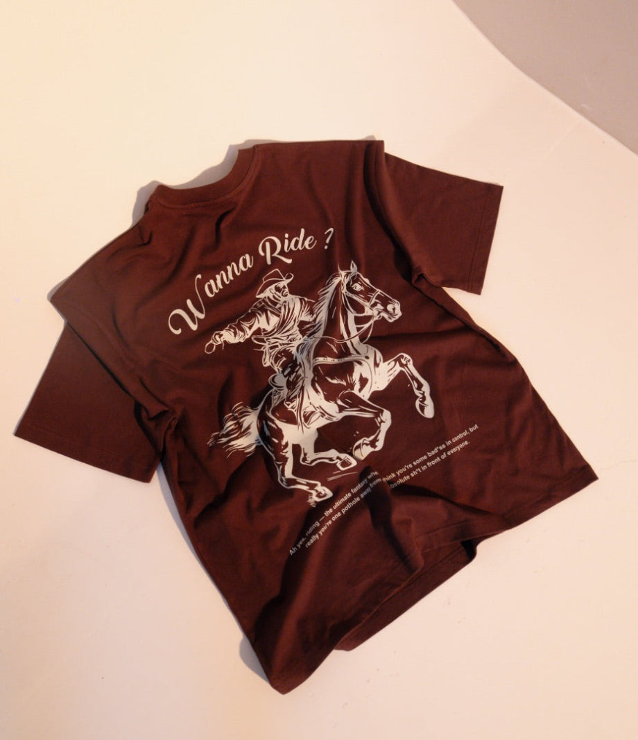 Brown t-shirt with horse graphic and 'Wanna Ride?' text on a light pink background
